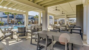 An outdoor patio area with a pool, lounge chairs, and tables.
