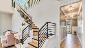 A modern interior with a staircase, wooden flooring, and a living area with a sofa and decorative items.