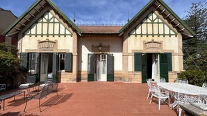 A traditional building with a tiled roof, green shutters, and a courtyard with outdoor seating. - Art Nouveau style villa facing Mondello beach (Palermo)