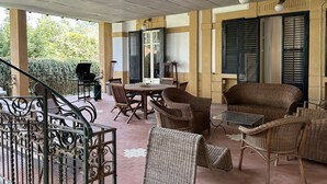 A covered outdoor seating area with wicker furniture, a table, and a grill. - Art Nouveau style villa facing Mondello beach (Palermo)