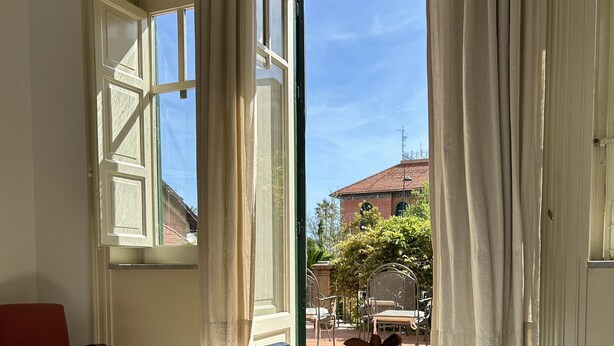 A hotel room with a bed, a red chair, and a view of the outside. - Art Nouveau style villa facing Mondello beach (Palermo)