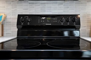 Enjoy cooking in this well-equipped kitchen with a stove, digital clock, and ample countertop space.