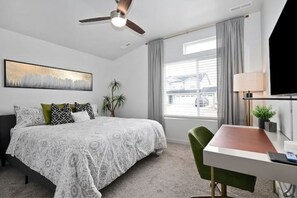 Relax in a stylish room with a neatly made bed, green chair, and large window offering a view of the outside.