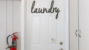 A white door with the word "laundry" on it, a fire extinguisher, and a small shelf with a framed photo and a toy. - Historic District, Downtown, STE 2 (Rapid City)