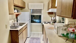 A compact kitchen with wooden cabinets, a built-in sink, a stove, and a microwave. - Historic District, Downtown, STE 2 (Rapid City)