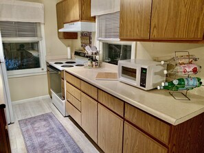 Una cocina con armarios de madera, estufa, microondas y una botella de agua con gas sobre la encimera.