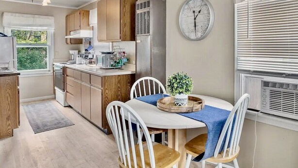 A modern kitchen with wooden cabinets, a built-in oven, and a dining area with a round table and chairs. - Historic District, Downtown, STE 2 (Rapid City)