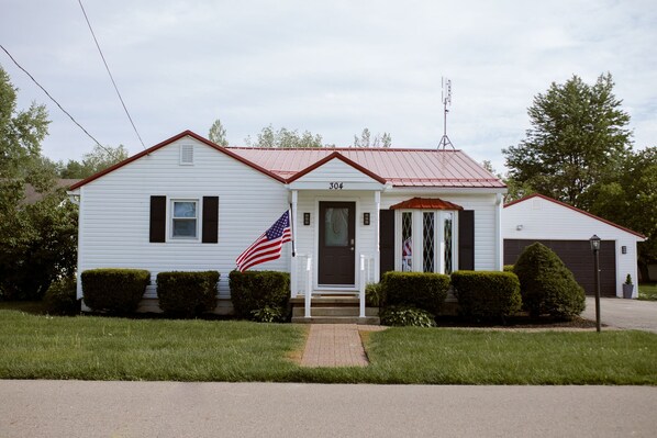 A white single-story house with a red roof, a front porch, and an American flag. - Heated Pool, Hot Tub, Game Room - Have fun with the ones you love! (Milford)