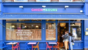 En blå butiksfasad med en skylt som visar texten ”CHICK IN SOURS” och en meny som listar rätter som friterad kyckling och drinkar.