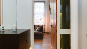 En smal hall som leder till ett vardagsrum med en soffa och ett fönster.