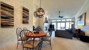 A spacious living room with a dining area, large windows, and a ceiling fan. - The Pointe at Lazy Days (Osage Beach)