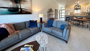 A spacious living area with two grey sofas, a coffee table, and a painting on the wall. - The Pointe at Lazy Days (Osage Beach)