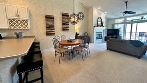 A modern living room with a dining area, a fireplace, and a large window. - The Pointe at Lazy Days (Osage Beach)