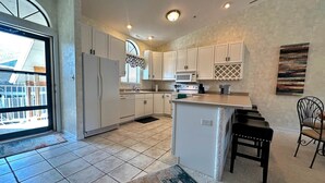 A modern kitchen with white cabinets, a central island, and a large window. - The Pointe at Lazy Days (Osage Beach)