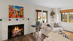 Una sala de estar con chimenea blanca, un sofá blanco y una silla verde.