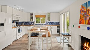 Una cocina moderna con armarios blancos, una mesa de comedor de madera y una chimenea.