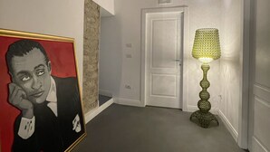 En gang med et indrammet portræt, en dør og en gulvlampe.
