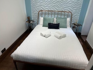 Relax in a stylishly designed room with a comfortable bed, wavy-patterned headboard, and modern side tables.
