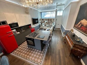 Enjoy cooking in the well-equipped kitchen with a gas stove and ample counter space, adjacent to a dining area with a wooden table and chairs.