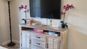 Ein Unterhaltungsschrank aus Holz mit einem Flachbildfernseher, einer Lampe und zwei Orchideen in Töpfen.