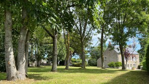A grassy area with trees and a stone building in the background.