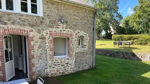 A stone building with a brick entrance, a small window, and a wooden deck with a table and chairs.