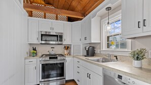 A modern kitchen with white cabinets, stainless steel appliances, and a wooden ceiling. - Outdoor Cape Cod Oasis just 5 minutes to S Village Beach! (Dennis)