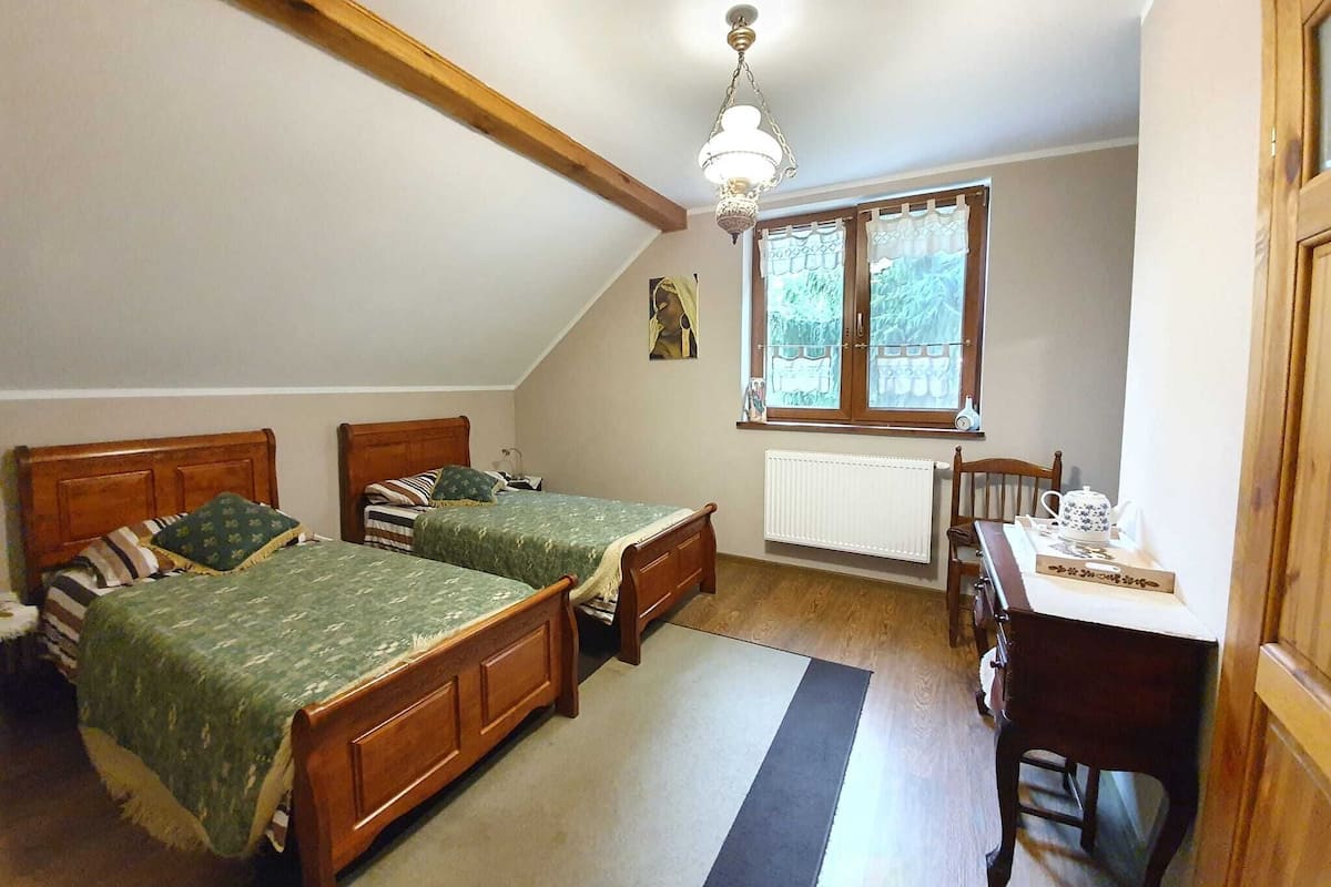 A bedroom with two wooden beds, a desk, and a radiator.
