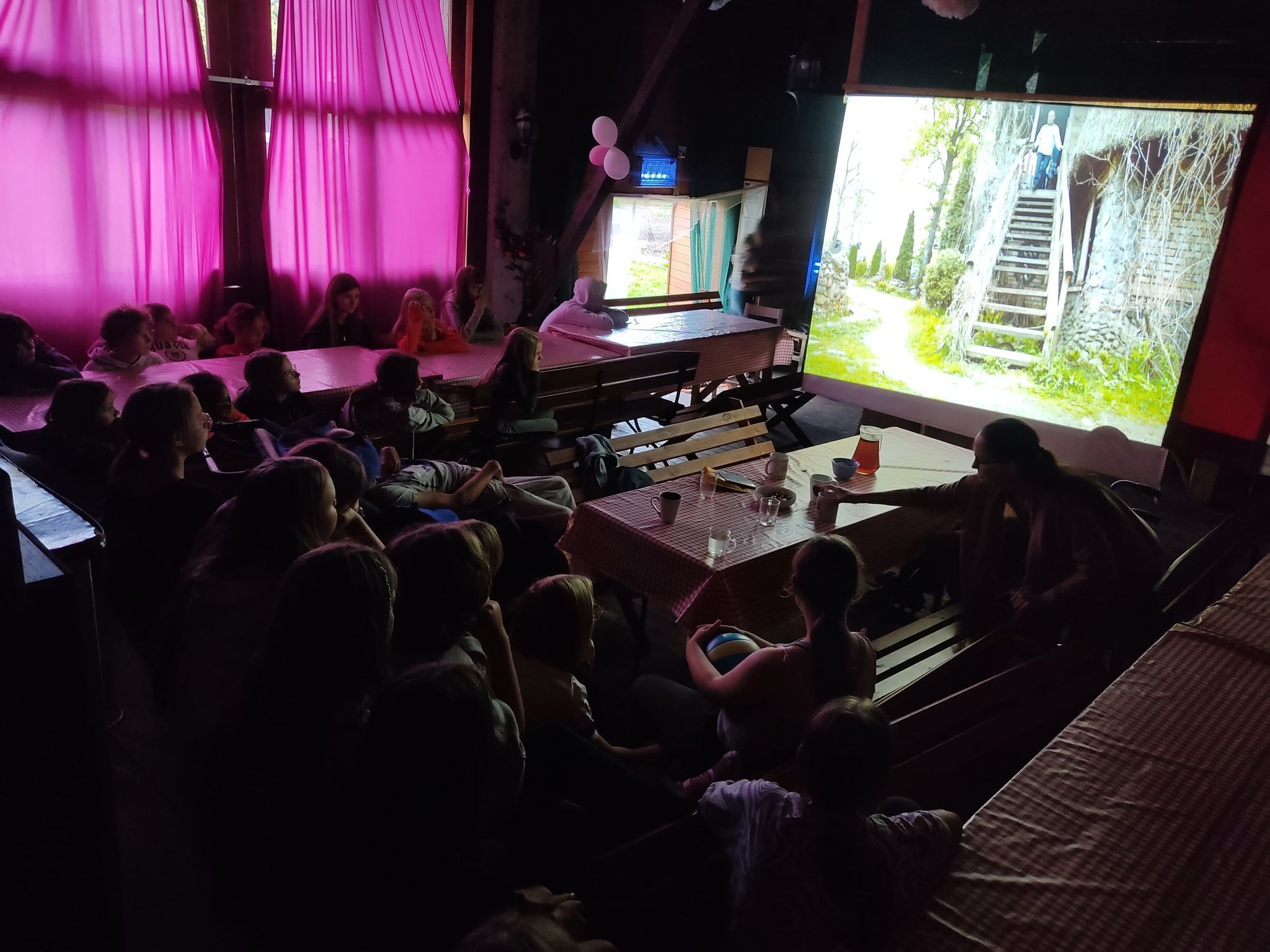 A dimly lit room with a stage and audience.