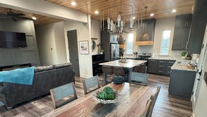 Una cocina moderna con suelo de madera, una isla central e iluminación colgante.