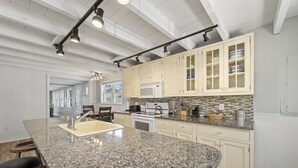 A kitchen with a granite countertop, white cabinets, and a built-in microwave. - 7-bedroom home that sleeps 14.  5-minute walk to Moody Beach (Wells)