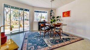 Un coin repas avec une grande fenêtre, un tapis à motifs zébrés et une table entourée de chaises.
