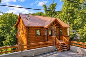 Eine Holzhütte mit Veranda und Treppe, umgeben von Bäumen.