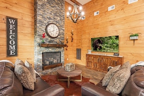 A cozy living room with a fireplace, leather sofas, a coffee table, and a television. - Brand New Luxury 3/3.5 Cabin Great Mountain Views, Hot Tub, Ober Gatlinburg Ski  (Gatlinburg)