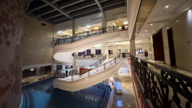 Un atrio de varios niveles con una fuente central, múltiples balcones y un diseño arquitectónico moderno.