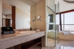 A modern bathroom with a large mirror, two sinks, a glass-enclosed shower, and a view of the city. - Jurong Yukun MOLTON Hotel (Jurong)