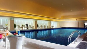 Zona de piscina con sillones de descanso y una mesa de vidrio.