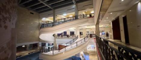 A multi-level atrium with a central spiral staircase, multiple balconies, and a pool area.