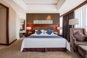 A hotel room with a large bed, a headboard with artwork, a nightstand with a lamp, a chair, and a view of the outdoors. - Jurong Yukun MOLTON Hotel (Jurong)
