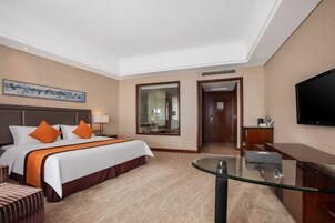 Una habitación de hotel con una cama grande, un escritorio, un televisor y un espejo.