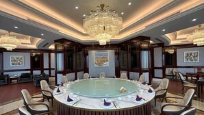 Un salón de conferencias con una mesa redonda de cristal, sillas alrededor y una gran lámpara de araña.