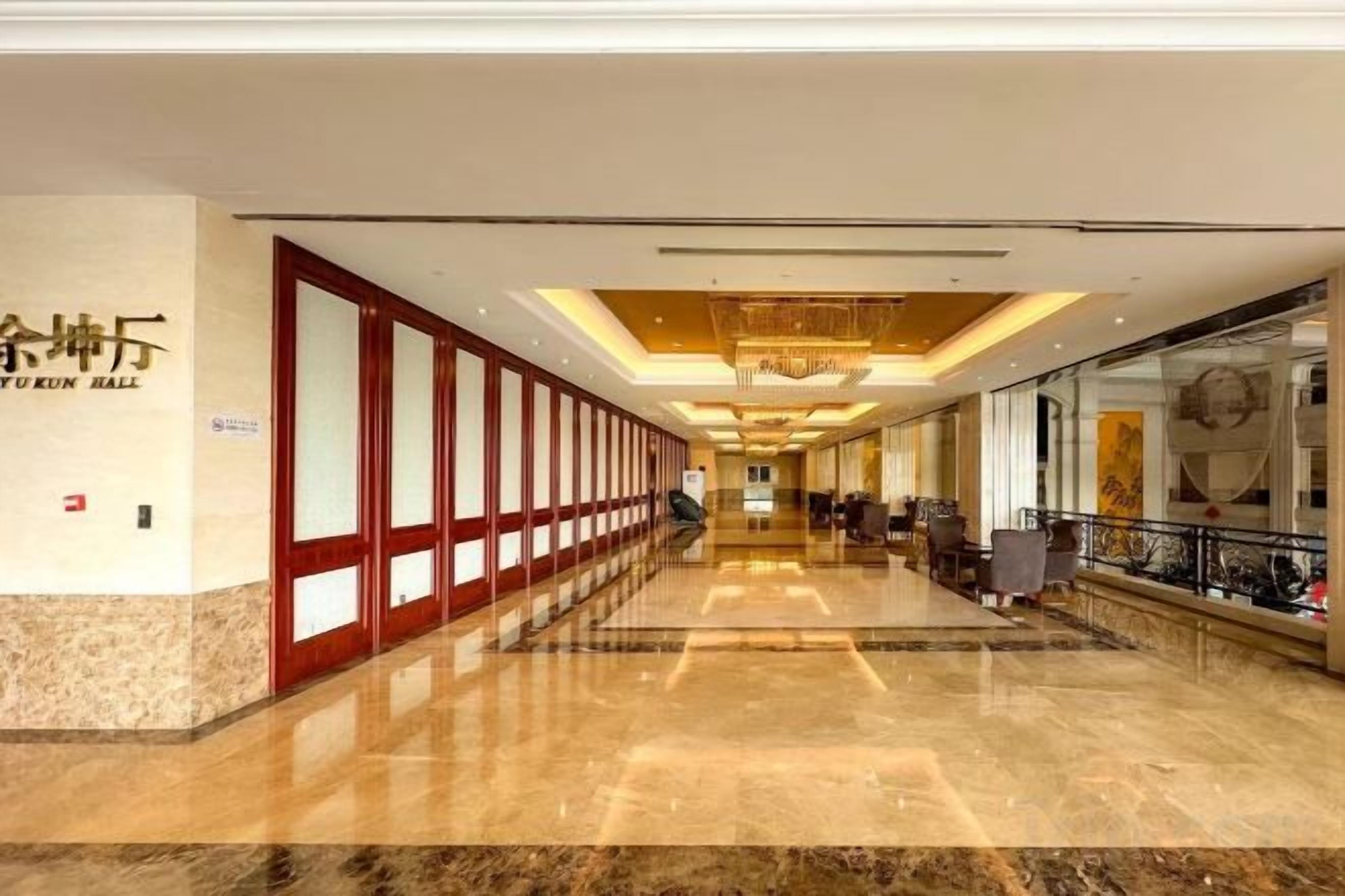 A hotel corridor with a polished marble floor, a reception area with a chandelier, and a sign indicating the hotel's name.