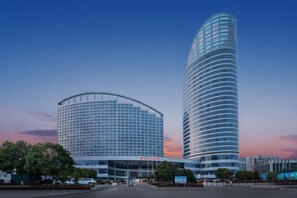 Un hotel moderno con fachada curva y un edificio cilíndrico alto con revestimiento de vidrio.
