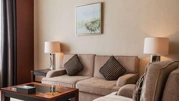 Ett hotellrum med en soffa, två lampor, en inramad tavla och ett litet bord.