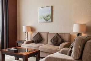 A hotel room with a sofa, two lamps, a framed picture, and a small table. - Jurong Yukun MOLTON Hotel (Jurong)