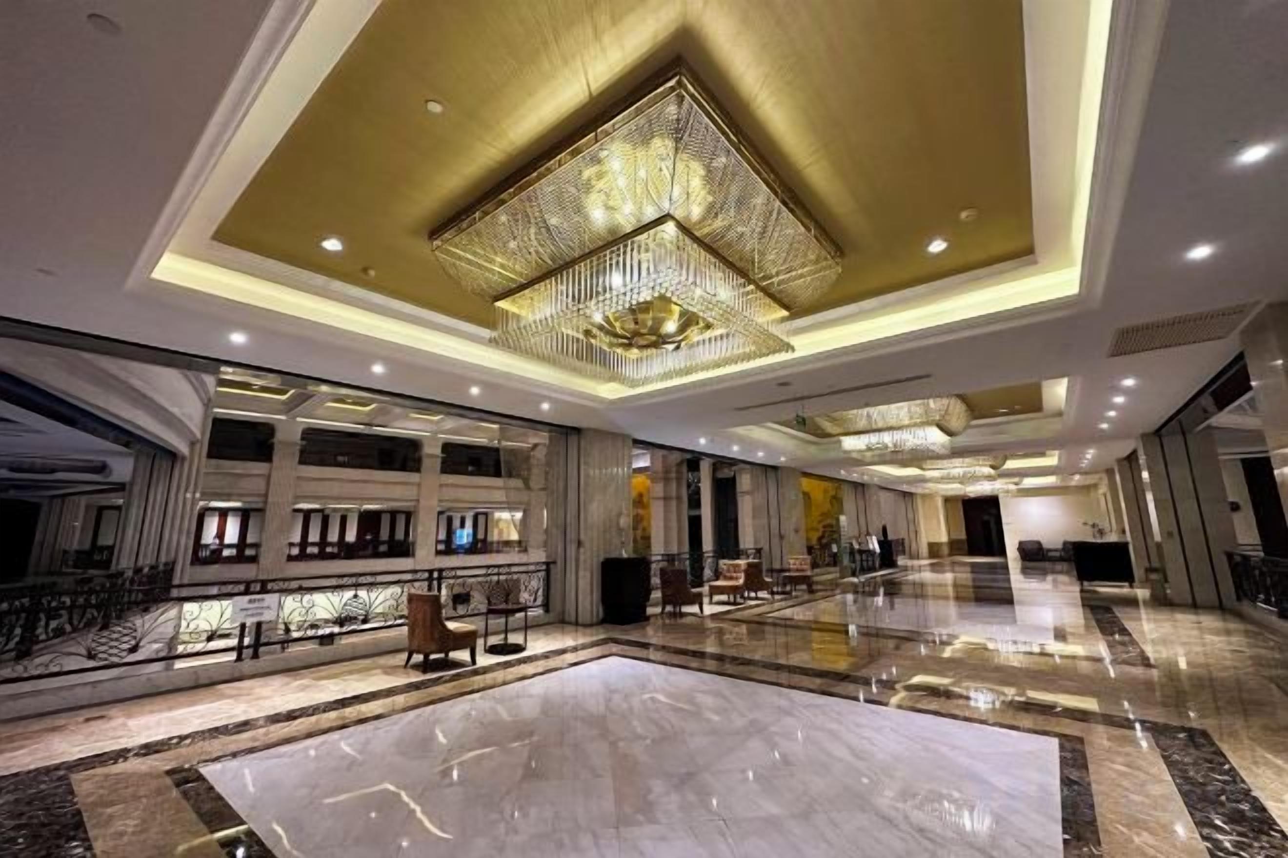 A spacious lobby with a large chandelier, marble flooring, and multiple seating areas.