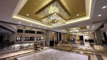A spacious lobby with a large chandelier, marble flooring, and multiple seating areas.