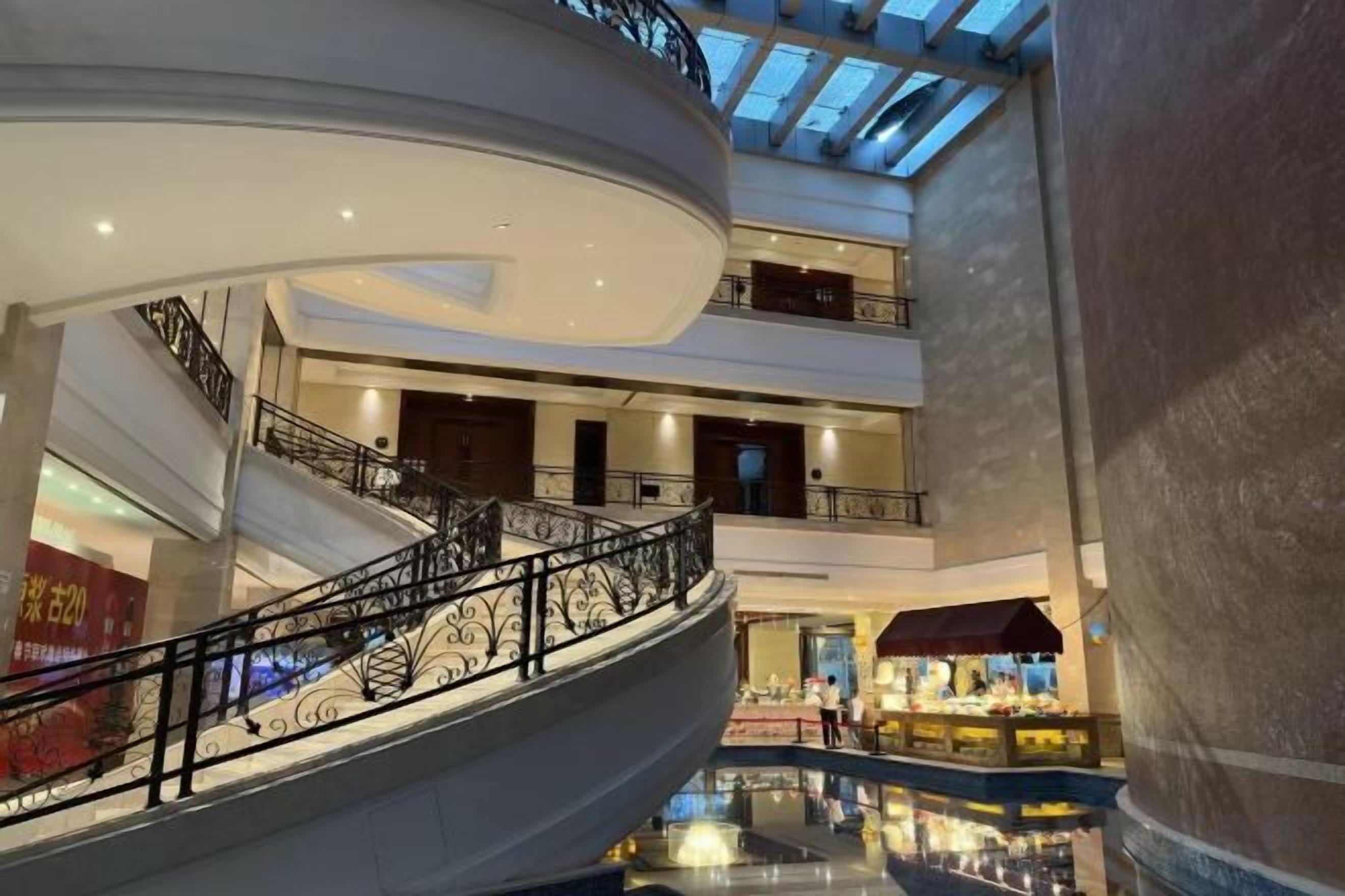 A multi-level shopping mall with a central atrium, glass ceiling, and a spiral staircase.
