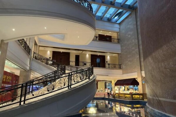 A multi-level shopping mall with a central atrium, glass ceiling, and a spiral staircase.