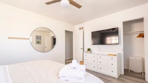 A modern bedroom with a large bed, a round mirror, a TV, and a wardrobe.